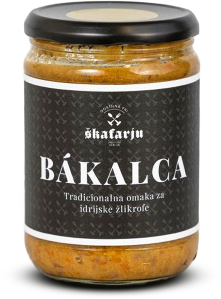 Kozarec omake Bákalca z črnim pokrovom in temno etiketo z napisom »BÁKALCA – Tradicionalna omaka za idrijske žlikrofe«, napolnjen z rjavo-oranžno omako.